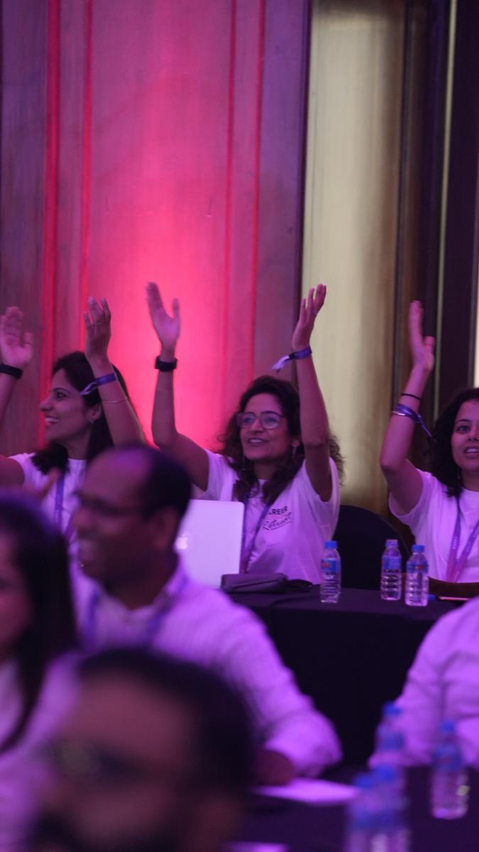Attendees with arms raised celebrating during a Career Grooming Retreat session